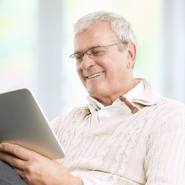 A mature man smiling while using his tablet