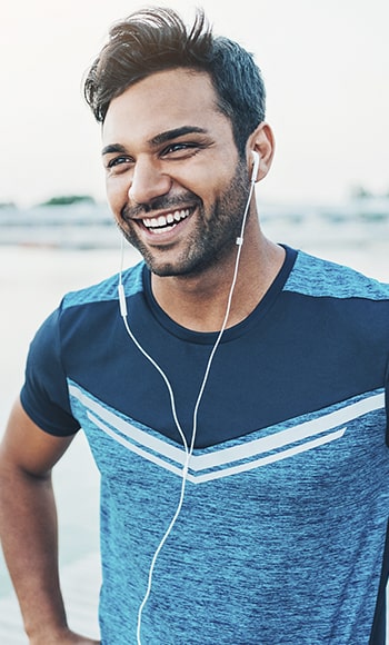 A young man wearing his headphones smiling