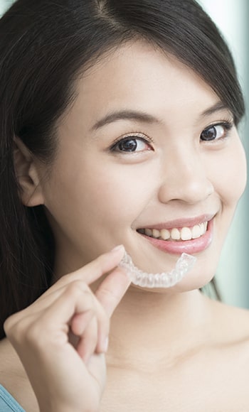 A young woman holding some Invisalign aligners